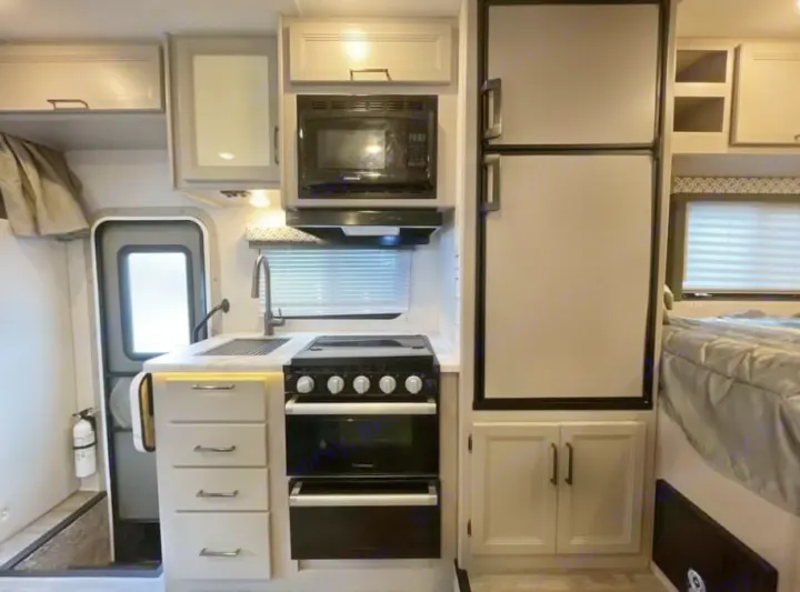 This rv rental offers a fully equipped kitchen with stove, microwave, fridge, sink, and cabinets, plus a comfortable sleeping area.. Thor Freedom Elite 2026