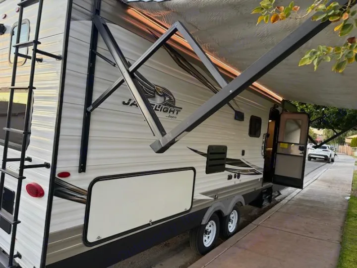 RV rental: A white Jayco Jay Flight travel trailer with its awning extended and door open, parked on a street, ready for adventure.. Jayco Jay Flight SLX Baja Edition 2019
