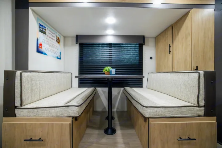 Enjoy this modern RV rental dinette with comfy benches, a table, window blinds, and cabinet storage for travel.. Forest River Campsite Reserve 17LS 2026