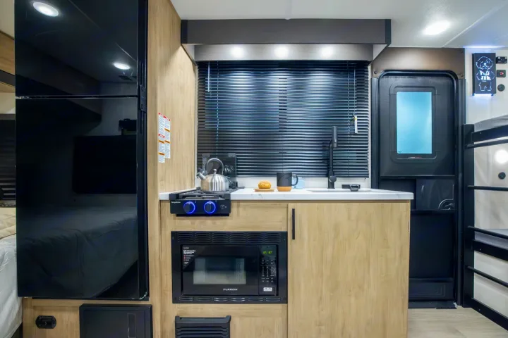 RV rental interior: a functional kitchenette with two-burner stove, microwave, sink, and full-size fridge.. Forest River Campsite Reserve 17LS 2026