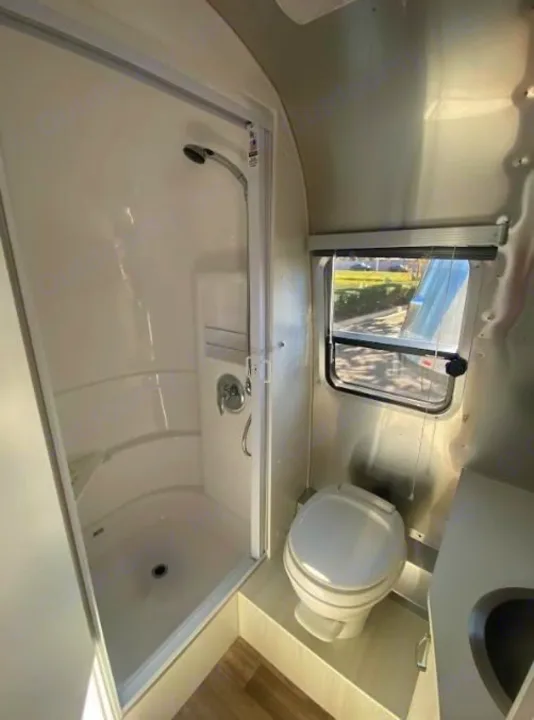 Clean RV rental bathroom featuring a full shower, toilet, and sink, designed for road trip comfort.. Airstream Bambi 2024