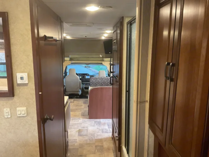 Inside this RV rental, a view from the rear shows the kitchen, bath, and driver's cab with an overhead bunk.. Forest River Sunseeker 2014