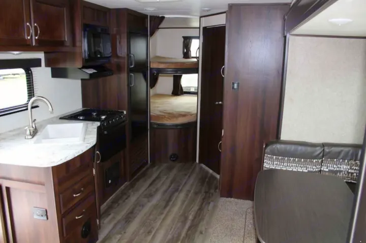 This RV rental interior features a full kitchen with sink/stove, bunk beds, and a cozy dinette, ideal for family travel.. Jayco Jay Flight SLX 2018