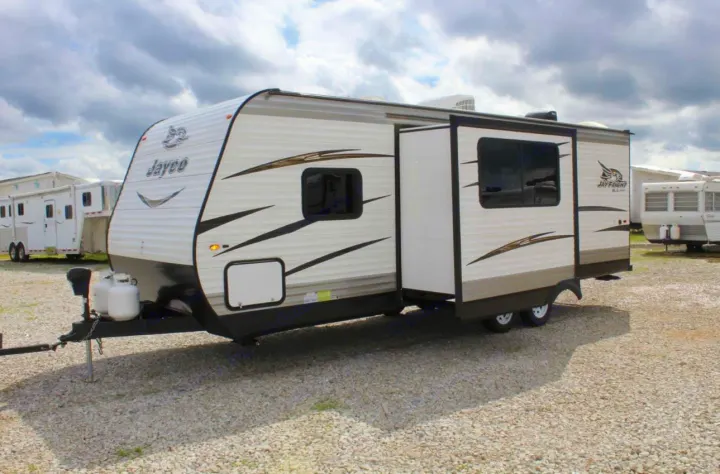 White Jayco travel trailer with an extended slide-out, ready for your RV rental camping trip on a gravel lot.. Jayco Jay Flight SLX 2018