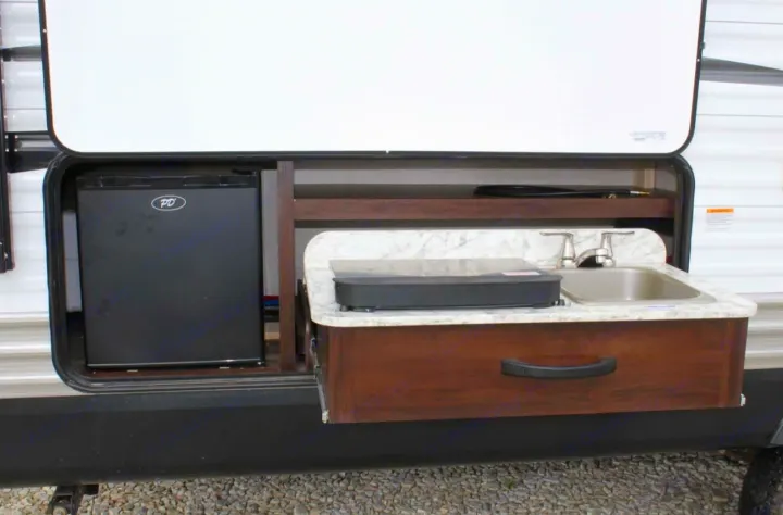 RV rental outdoor kitchen: a pull-out counter with sink and cooktop, plus a compact fridge for convenient camp cooking.. Jayco Jay Flight SLX 2018