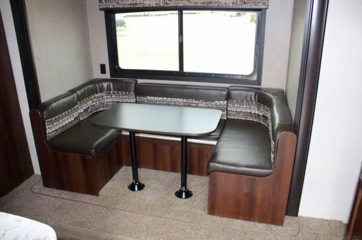 RV rental dinette featuring U-shaped booth seating with dark brown leather and patterned fabric, and a gray table.. Jayco Jay Flight SLX 2018
