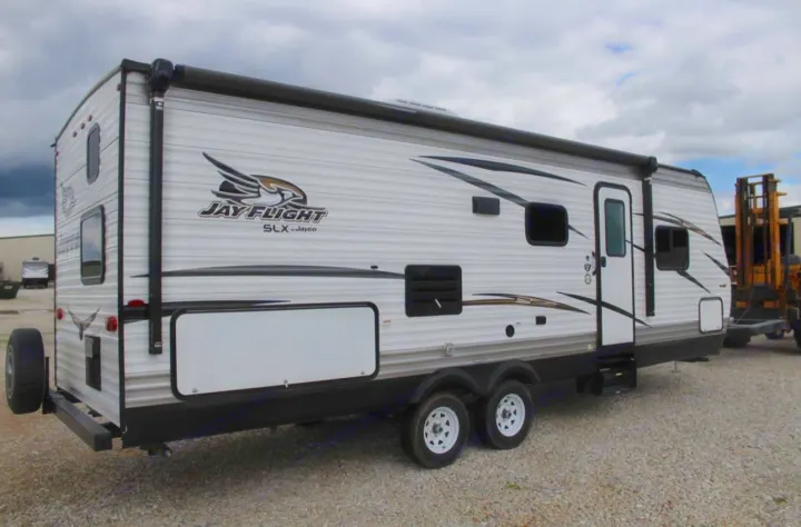 Side view of a white and grey Jay Flight SLX travel trailer on a gravel lot, ideal for your next rv rental trip.. Jayco Jay Flight SLX 2018
