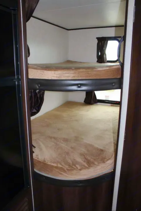 Cozy rv rental bunk beds with tan mattresses inside a compact RV, perfect for family travel or camping adventures.. Jayco Jay Flight SLX 2018
