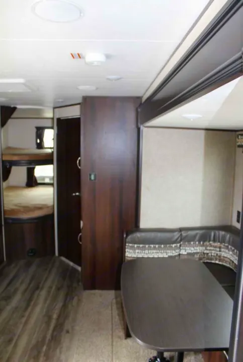 Interior of an RV rental featuring bunk beds on the left and a U-shaped dinette with a table on the right.. Jayco Jay Flight SLX 2018