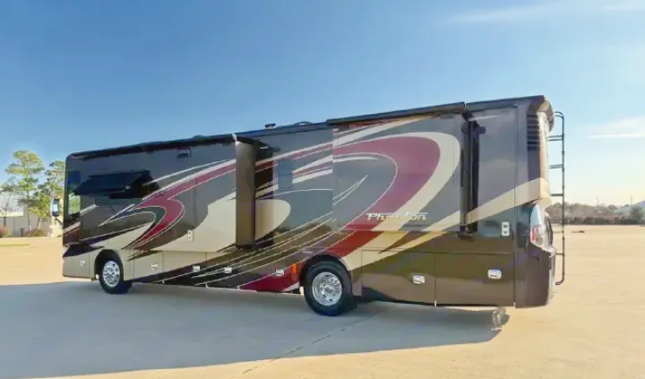 Luxury Tiffin Phaeton rv rental. Sleek dark motorhome with red/tan stripes, parked on asphalt under a blue sky.. Tiffin Phaeton 36 QHS 2015