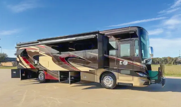Luxurious brown RV rental with extended slide-outs and awnings, parked on asphalt under a blue sky, ideal for travel.. Tiffin Phaeton 36 QHS 2015