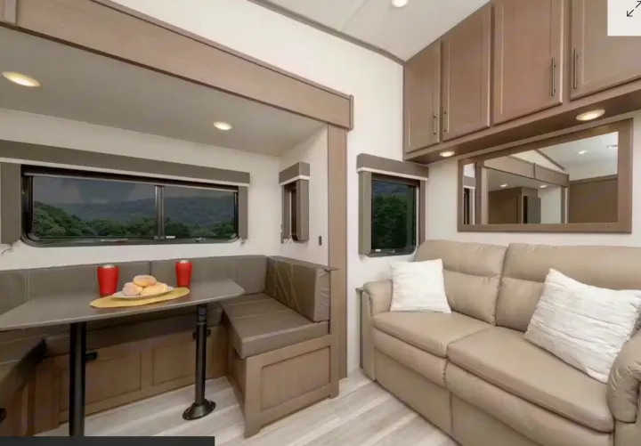 Modern RV rental interior features a cozy dinette, plush sofa, storage cabinets, and scenic windows for your next adventure.. Keystone RV Cougar 2022