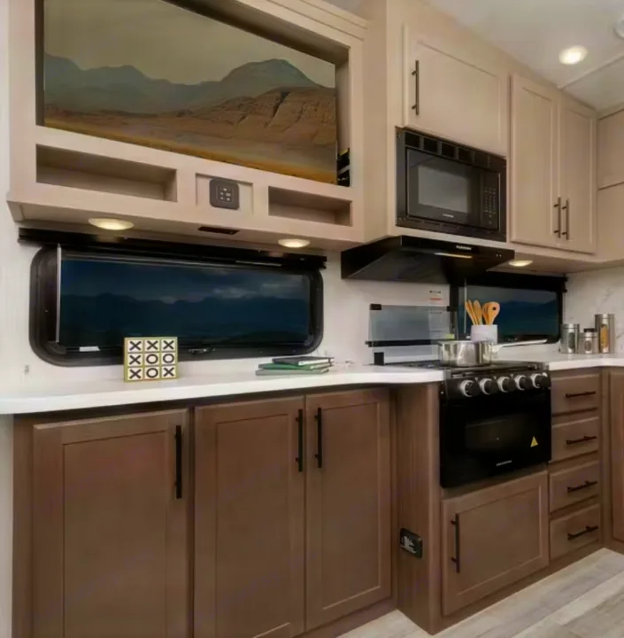Stylish RV kitchen in an RV rental unit, featuring a full stove, microwave, and mountain views from the windows.. Keystone RV Cougar 2022