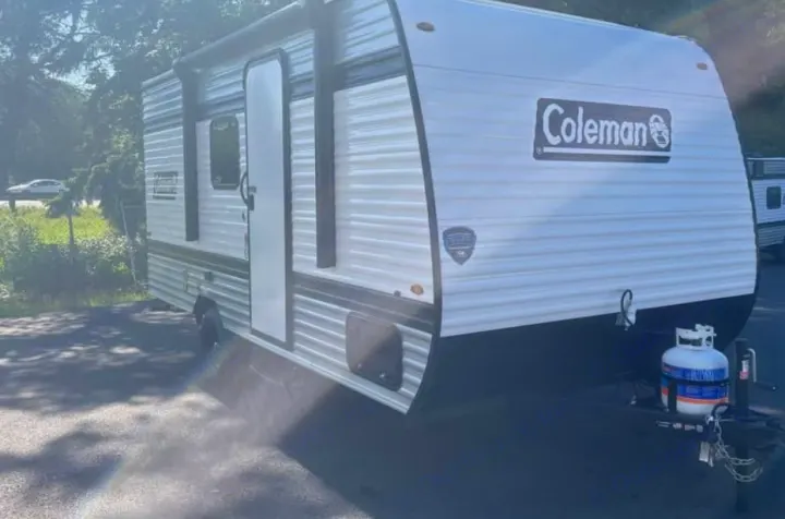 Coleman travel trailer RV rental, white & black exterior. Features propane tank, ready for your camping or outdoor adventure.. Keystone RV Coleman 2025