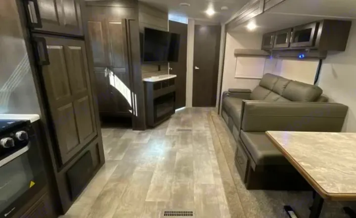 Explore this rv rental's spacious living area: kitchen, entertainment center, comfy sofa, and dinette. Ideal for travel.. Keystone RV Flagstaff Super Lite 2023
