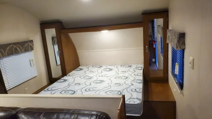This RV rental bedroom features a comfy bed, built-in storage, window blinds, and overhead lighting for your travels.. Forest River Wildwood X-Lite 2018