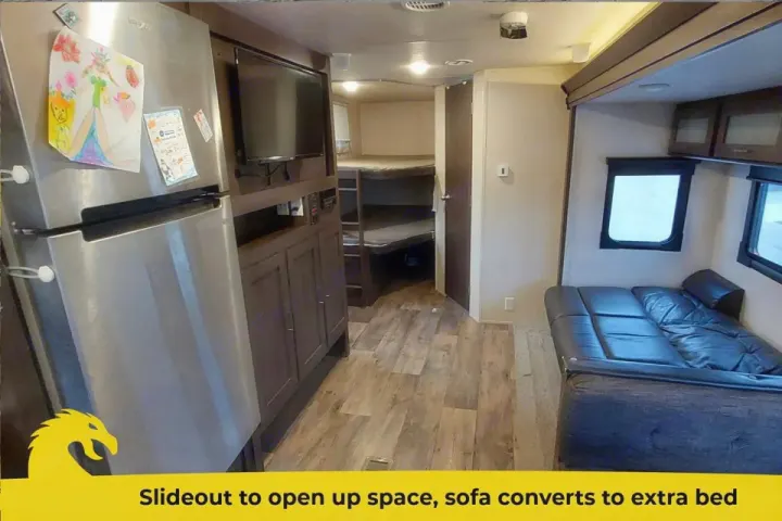Spacious RV rental interior with fridge, entertainment center, bunk beds, and a slide-out sofa that converts to a bed.. Forest River Salem 2018
