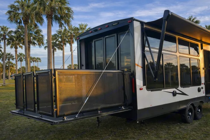 Experience this RV rental featuring a rear patio deck, extended awning, and large windows. Perfect for outdoor living among palm trees.. Forest River Wildwood FSX Platinum 2023