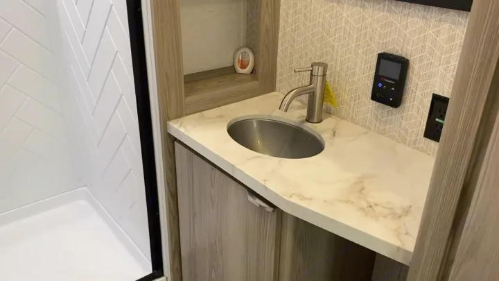 RV rental bathroom features a compact shower, vanity with sink, and control panel for convenience.. Forest River Wildwood FSX Platinum 2023