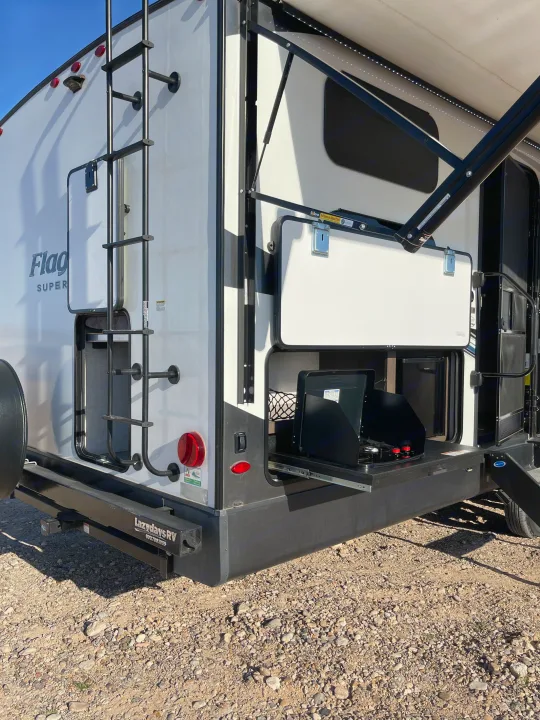 This RV rental features a convenient outdoor kitchen with a stove, an extended awning, and a rear ladder, perfect for camping.. Forest River Flagstaff Super Lite 2021