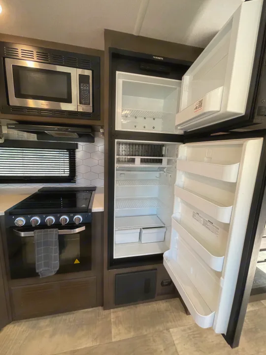 Spacious and clean RV rental kitchen featuring a Dometic refrigerator, microwave, and stove with oven.. Forest River Flagstaff Super Lite 2021