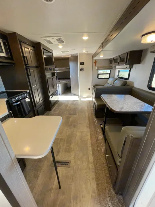 Modern RV rental interior showing kitchen, dining, living areas, and bunk beds, with light wood-look flooring.. Forest River Flagstaff Super Lite 2021