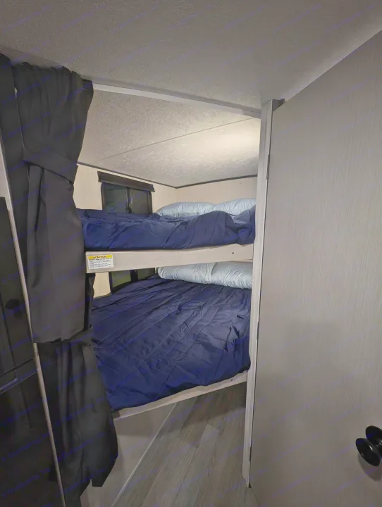 Compact rv rental bunk beds with navy bedding and light pillows, nestled in a cozy RV sleeping area.. Coachmen Apex Nano 2025