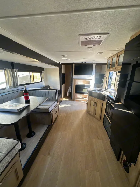 Explore this modern rv rental interior: bright kitchen, dinette, and living space with light wood floors. Perfect for your travels.. Forest River Cherokee Grey Wolf 2026