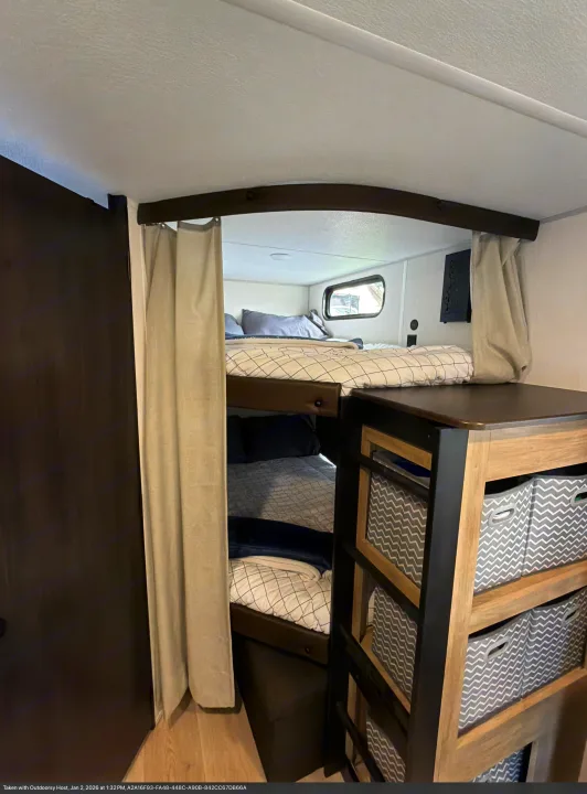 Cozy RV rental bunk beds feature privacy curtains, a window, and built-in storage cubbies with chevron bins.. Forest River Cherokee Grey Wolf 2026