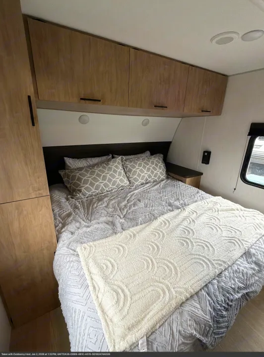 Cozy RV rental bedroom with wooden overhead cabinets, a comfortable bed, gray and white bedding, and recessed lighting.. Forest River Cherokee Grey Wolf 2026