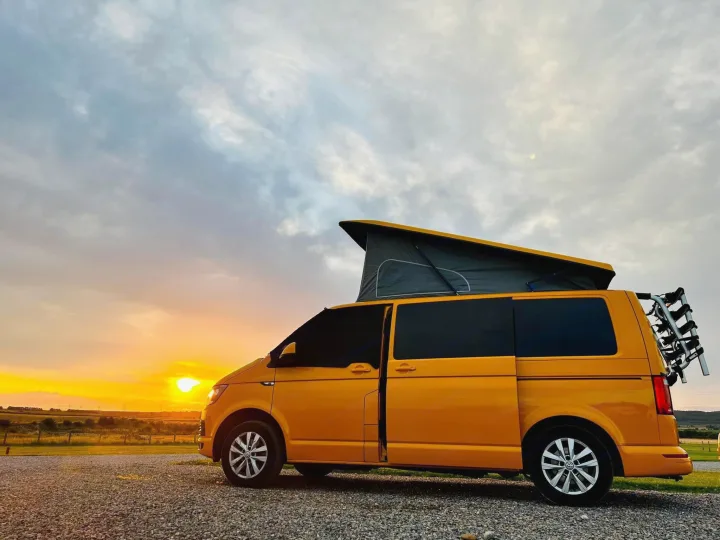 Bright yellow camper van with pop-top roof & bike rack, parked on gravel at sunset. Perfect for your next rv rental adventure!. Volkswagen T6 transporter 2019