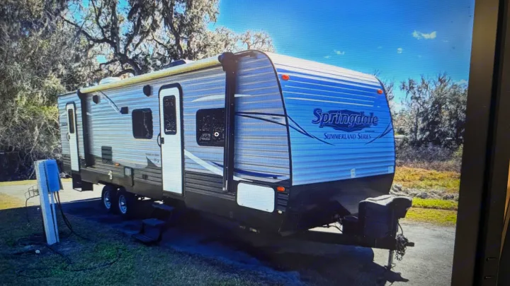 Light blue & gray Springdale Summerland Series travel trailer parked at a sunny campsite. Ideal for your next rv rental trip!. Springdale sm2820bh16 2016