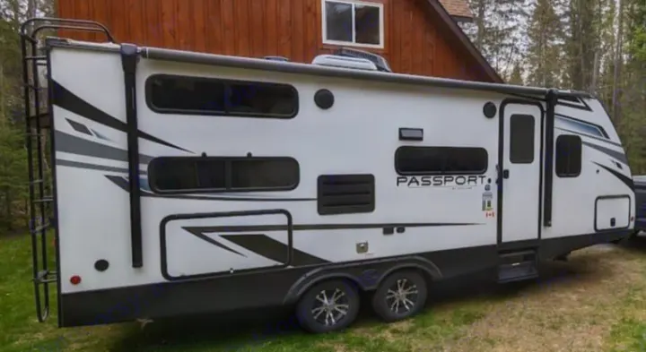 White Passport travel trailer RV rental, parked on grass. This recreational vehicle is ready for your next outdoor adventure.. Keystone RV Passport SL 2021