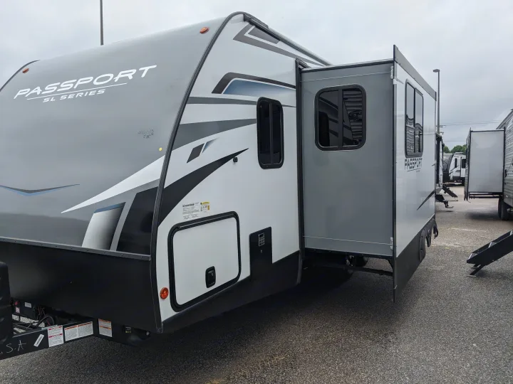 This grey and white Passport SL Series travel trailer, with its side slide-out extended, is ready for your next RV rental adventure.. Keystone RV Passport SL 2021
