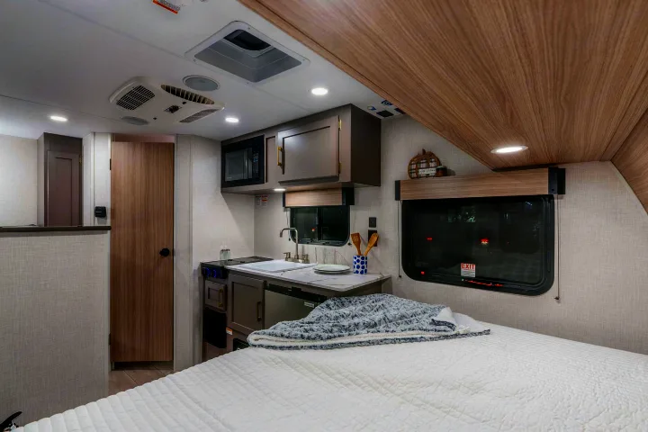 Step inside this modern RV rental featuring a compact kitchen, comfortable bedroom, and all the essentials for your next adventure.. KZ Sportsmen Classic 130BH 2026