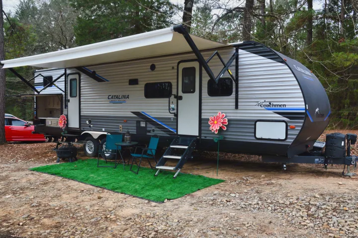 A Coachmen Catalina travel trailer RV rental, featuring an extended awning, outdoor kitchen, and cozy campsite setup.. Coachmen Catalina 2022