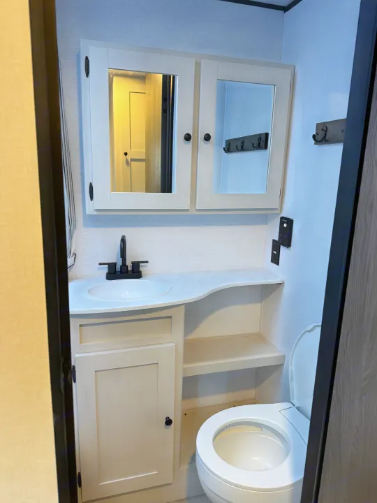 Modern, compact bathroom in an rv rental, featuring a white sink, light wood vanity, toilet, and mirrored medicine cabinet.. Coachmen Spirit 29BH 2026