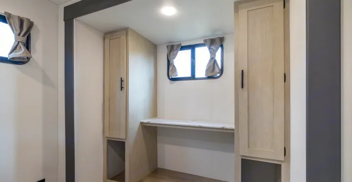 Modern RV rental interior: a compact desk with storage, two windows, and a bright, functional workspace.. Forest River Shasta I-5 2025