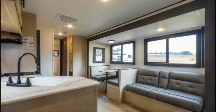 Modern RV rental interior with a bright kitchen, dining booth, and comfortable sofa, perfect for your next adventure.. Forest River Shasta I-5 2025