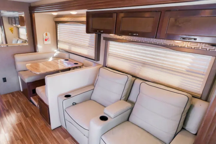 Spacious RV rental interior with a cozy dinette, modern overhead cabinets, and comfortable theater seating with cup holders.. Thor A.C.E. 2018