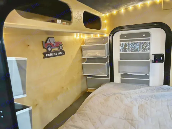 Explore a cozy RV rental: comfy bed, string lights, and clever storage solutions for your next adventure.. Outbound Trailer Outbound Extreme 2026