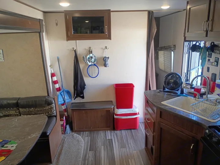 This inviting RV rental interior features a compact kitchen with sink, cozy dinette, and wall hooks for organized storage on the road.. Jayco Jay Flight SLX 2017