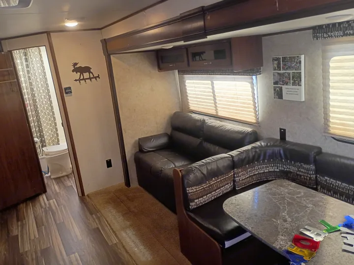 Cozy RV rental interior featuring a leather sofa, dining area, and a glimpse of the bathroom.. Jayco Jay Flight SLX 2017