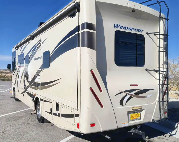 Cream WindSport RV rental parked, showing side and rear with a ladder, ready for a road trip.. Thor Windsport 2017
