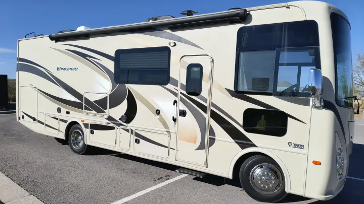 This cream Thor Windsport RV rental, with stylish black and tan graphics, is parked outdoors, ready for your next adventure.. Thor Windsport 2017
