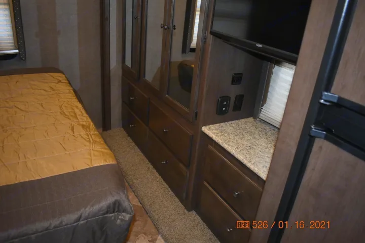 RV rental bedroom with a bed, mirrored closet, drawers, and a Vizio TV. Provides comfort and storage for your trip.. Thor Windsport 2017
