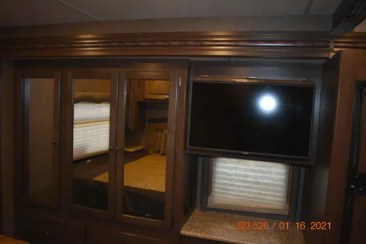 RV rental bedroom featuring a mounted TV, mirrored wardrobe, and reflected bed, showcasing functional design and storage.. Thor Windsport 2017