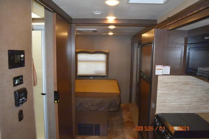 RV rental interior: bedroom with bed, kitchen (microwave, fridge, stovetop), and control panel. Shower visible. Ready for adventure!. Thor Windsport 2017