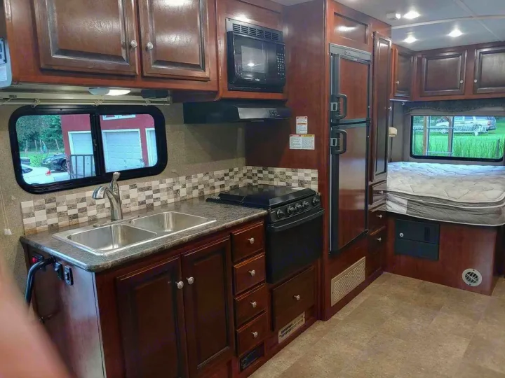 Cozy RV rental interior featuring a well-equipped kitchen, fridge, and comfortable bed. Ready for your travels.. Holiday Rambler Altera 2018