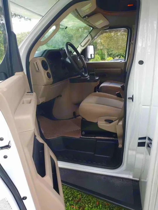 View of an RV rental's driver's cabin: beige seats, steering wheel, dashboard, & open door. Ready for your road trip adventure.. Holiday Rambler Altera 2018